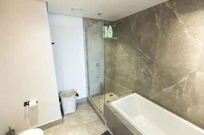 a bathroom with a shower and a bath tub at City Nest - Heart of Waterfall in Midrand