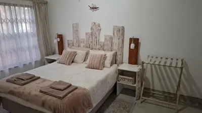 a bedroom with a large bed with a wooden headboard at The Big Tree selfcatering accommodation in White River