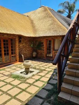 a house with a thatched roof and a stone patio at Khaya Africa Guesthouse in Midrand