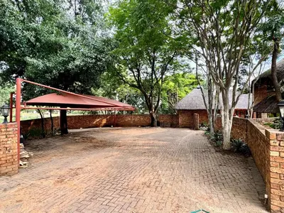 a brick parking lot with a red roof and a brick wall at Khaya Africa Guesthouse in Midrand