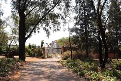 a path in a park with trees and a gate at Khaya Africa Guesthouse in Midrand