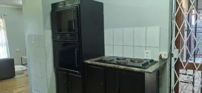 a kitchen with a stove and a black refrigerator at Sandgrouse Guesthouse in Centurion