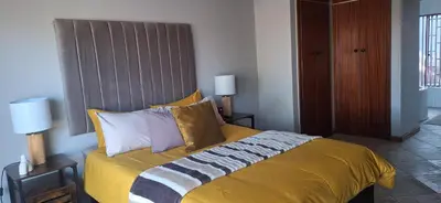 a bedroom with a bed with yellow sheets and pillows at Sandgrouse Guesthouse in Centurion