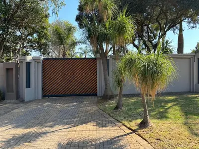 a fence with palm trees in front of a driveway at 72 on Devenish in Polokwane