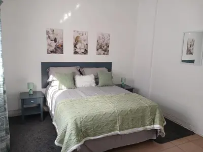 a bedroom with a bed with two tables and two pictures on the wall at The Garden Cottage in Polokwane