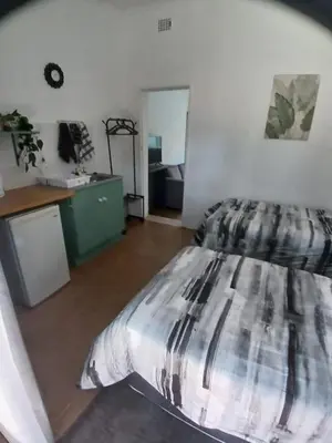 a bedroom with a large bed and a desk at The Garden Cottage in Polokwane