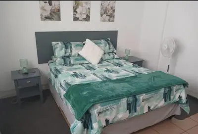 a bedroom with a bed with a green comforter at The Garden Cottage in Polokwane