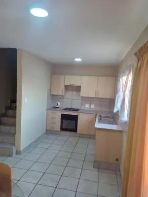 a kitchen with a stove top oven next to a staircase at Tranquil heights Inn in Centurion