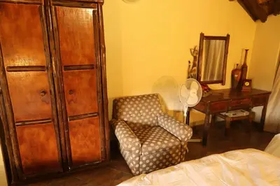 a bedroom with a chair and a dresser and a mirror at Tanda Kutula Mountain Lodge in Guthrie