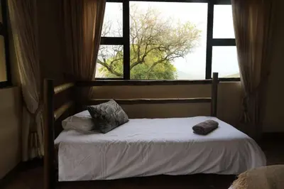 a bed with two pillows and a window at Tanda Kutula Mountain Lodge in Guthrie