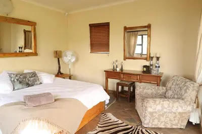 a bedroom with a bed and a chair and a mirror at Tanda Kutula Mountain Lodge in Guthrie