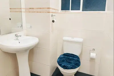 a white bathroom with a toilet and a sink at Panaroma View in Graskop