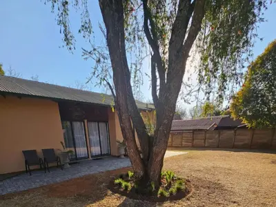 a tree in a yard in front of a building at Protea Guesthouse in Middelburg