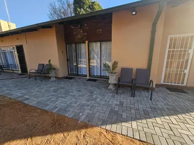 a patio in front of a house with chairs at Protea Guesthouse in Middelburg