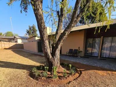 a tree in a yard in front of a house at Protea Guesthouse in Middelburg
