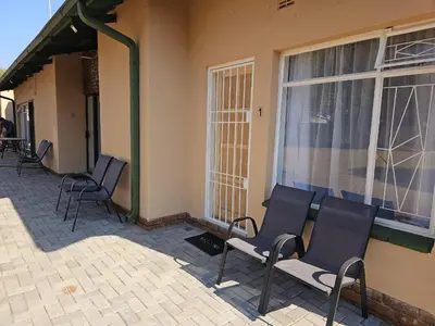a group of chairs sitting on the side of a building at Protea Guesthouse in Middelburg