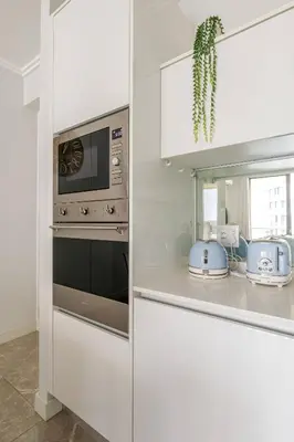 a white kitchen with a microwave and a stove at Shapz at Ellipse-Waterfall in Midrand