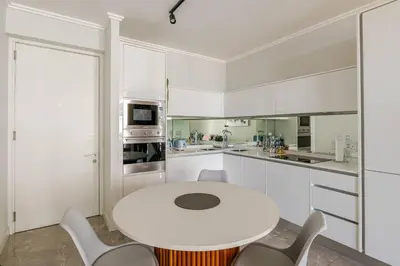 a white kitchen with a white table and chairs at Shapz at Ellipse-Waterfall in Midrand