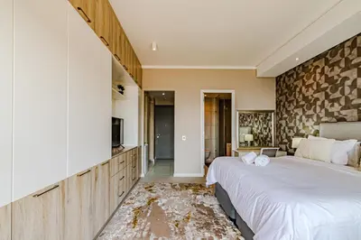 a bedroom with a large bed and a stone wall at 1403 Menlyn Maine Trilogy in Pretoria