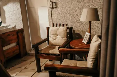 a room with a chair and a table and a lamp at A Traveller's Palm in Phalaborwa