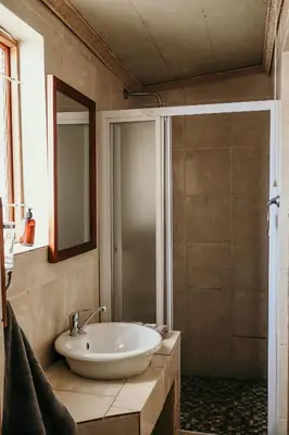 a bathroom with a white sink and a shower at A Traveller's Palm in Phalaborwa