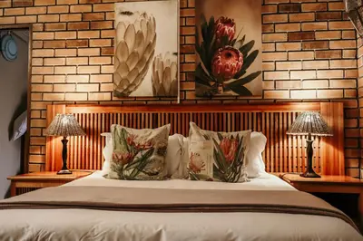 a bedroom with a bed with pillows and two lamps at A Traveller's Palm in Phalaborwa