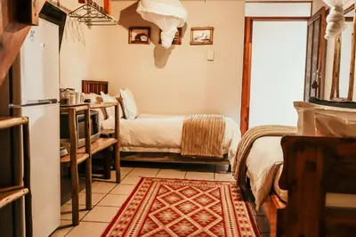 a room with two beds and a kitchen with a refrigerator at A Traveller's Palm in Phalaborwa