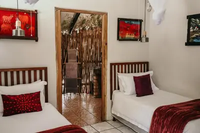 a bedroom with two beds and a door to a room at A Traveller's Palm in Phalaborwa