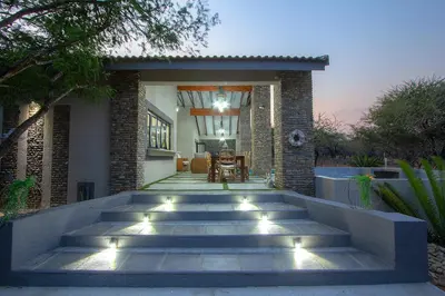 a house with stairs leading to a patio with lights at Edjami Lodge in Marloth Park