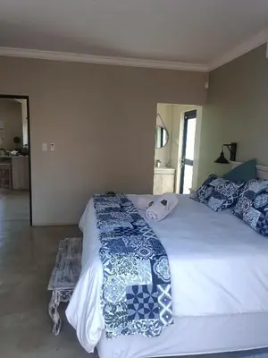 a bedroom with a large white bed with blue pillows at Edjami Lodge in Marloth Park
