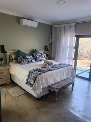 a bedroom with a bed with a teddy bear on it at Edjami Lodge in Marloth Park