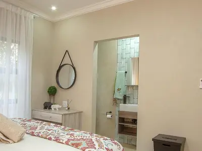 a bedroom with a bed and a mirror and a sink at Edjami Lodge in Marloth Park