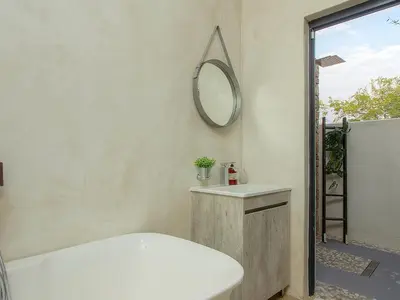 a bathroom with a white tub and a mirror at Edjami Lodge in Marloth Park