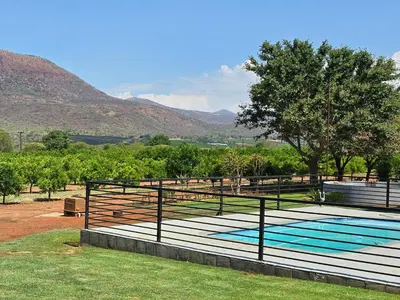 a swimming pool with mountains in the background at Die Boom Guest Farm in Boerboomskraal