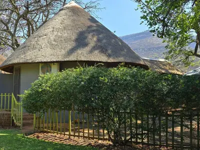 a house with a thatched roof with a fence at Die Boom Guest Farm in Boerboomskraal