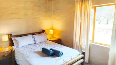 a bedroom with a bed with two blue pillows on it at Modubu Lodge in Bela-Bela