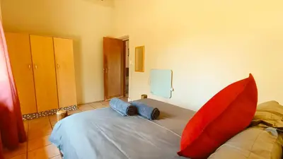 a bedroom with a bed with red pillows on it at Modubu Lodge in Bela-Bela