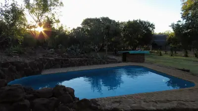 a swimming pool in a yard with a stone wall at Modubu Lodge in Bela-Bela