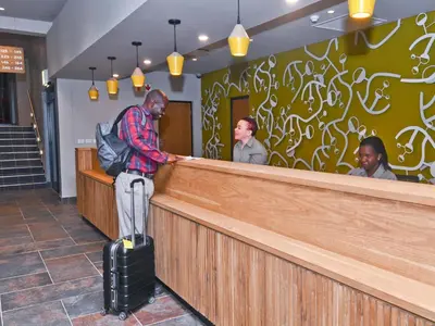 a man standing at a counter with his luggage at aha Skukuza Safari Lodge in Skukuza