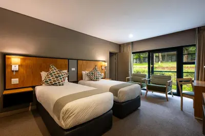 a hotel room with two beds and a chair at aha Skukuza Safari Lodge in Skukuza
