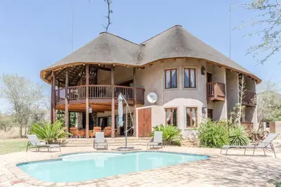 a large house with a thatched roof and a pool at Zebula Lodge 132 in Mabula