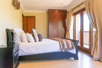 a bedroom with a bed with white sheets and a window at Zebula Lodge 132 in Mabula