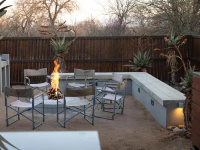 a patio with a table and chairs and a fire pit at Ntoma House in Hoedspruit