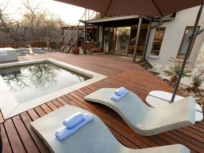 a pool with two lounge chairs and towels on a deck at Ntoma House in Hoedspruit