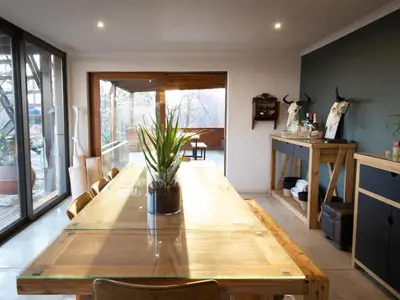 a dining room with a wooden table with a plant on it at Ntoma House in Hoedspruit