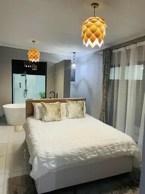 a bedroom with a bed and a tub and a chandelier at Tranquil Unit in Phalaborwa