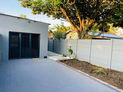 a white building with a door and a fence at Tranquil Unit in Phalaborwa