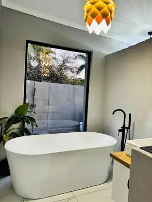a large white bath tub in a room with a window at Tranquil Unit in Phalaborwa