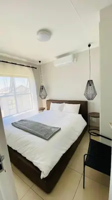 a bedroom with a large white bed with two pendant lights at Irenes home of nature in Nelspruit