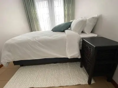 a bed with white sheets and pillows next to a window at LA Montranquilo-Home of comfort in Pretoria